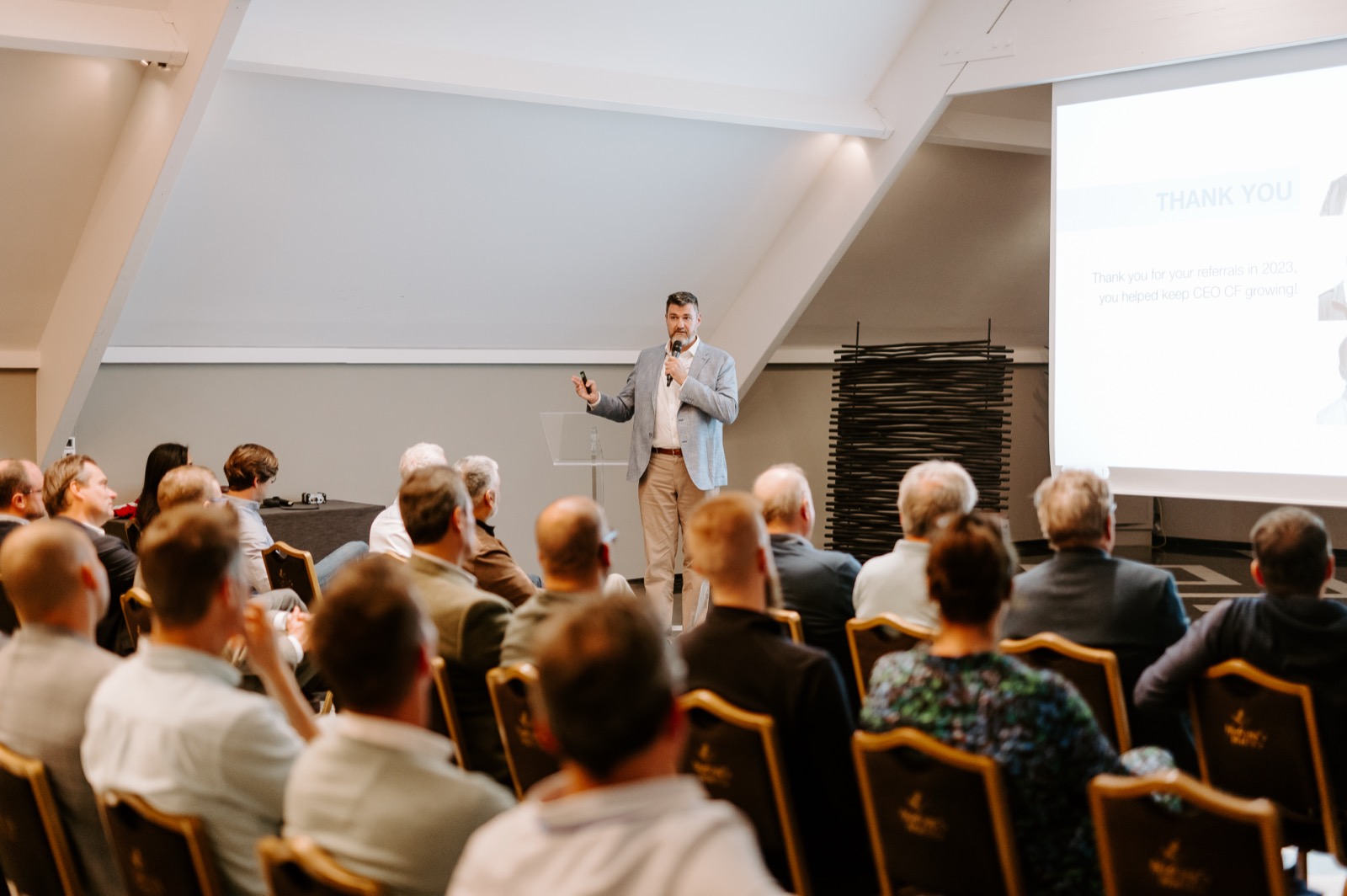 Tony Wood presenting to an audience in a conference room.