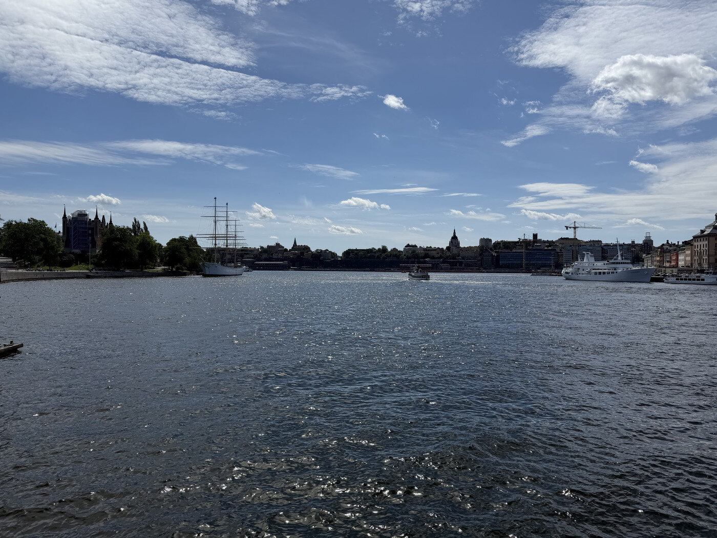 A wide scenic view across Stockholm harbour with boats, water, and a bright sky.